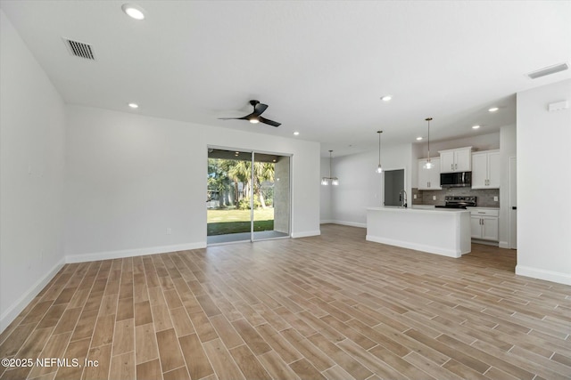 unfurnished living room featuring ceiling fan, light hardwood / wood-style flooring, and sink