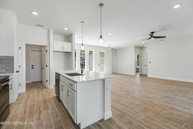 kitchen with a center island with sink, sink, ceiling fan, decorative light fixtures, and white cabinetry