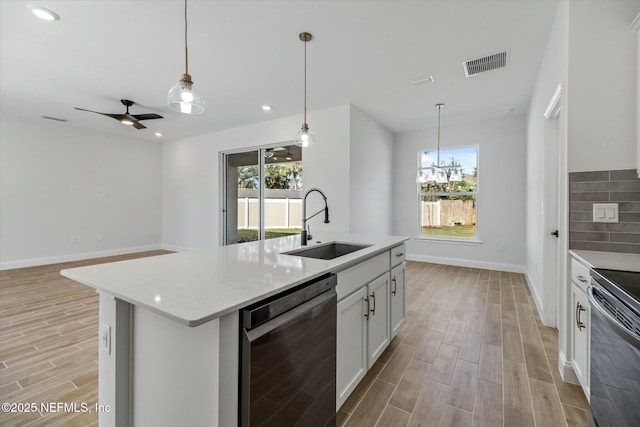 kitchen featuring sink, stainless steel appliances, an island with sink, white cabinets, and ceiling fan with notable chandelier