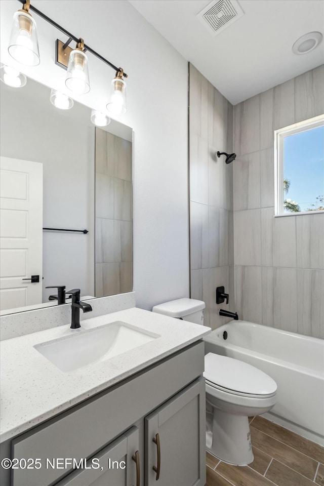 full bathroom featuring vanity, tiled shower / bath combo, and toilet