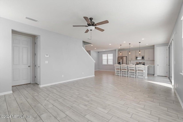 unfurnished living room featuring light hardwood / wood-style flooring and ceiling fan