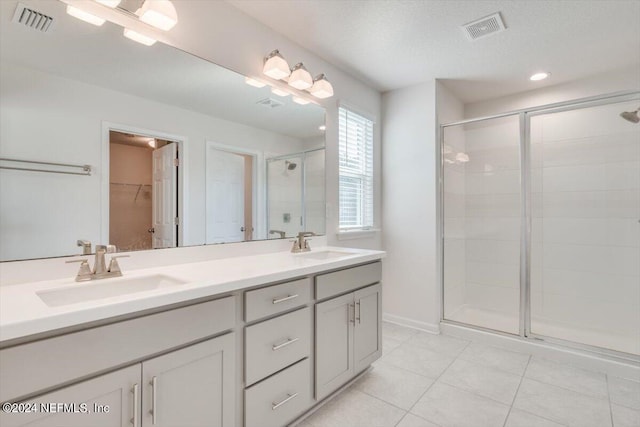 bathroom with tile patterned flooring, walk in shower, vanity, and a textured ceiling