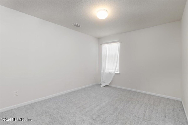 carpeted spare room with a textured ceiling