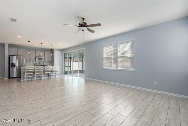 unfurnished living room with light wood-type flooring and ceiling fan