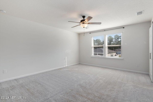 unfurnished room featuring light carpet, a textured ceiling, and ceiling fan