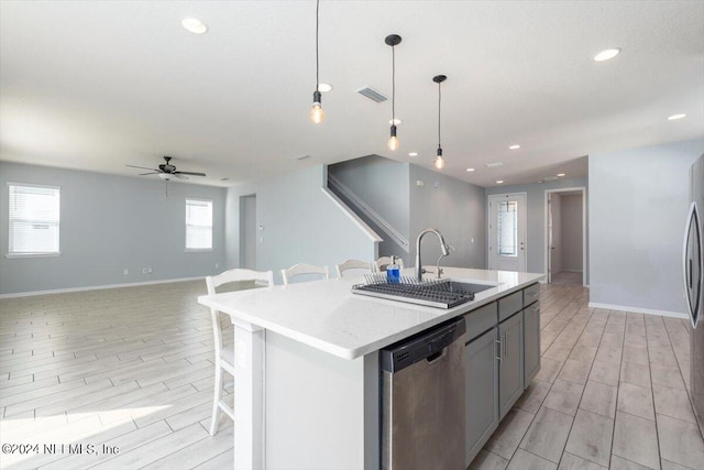 kitchen featuring light hardwood / wood-style flooring, a kitchen breakfast bar, decorative light fixtures, sink, and appliances with stainless steel finishes