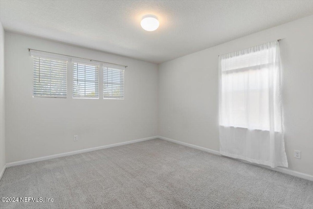 carpeted empty room with a textured ceiling