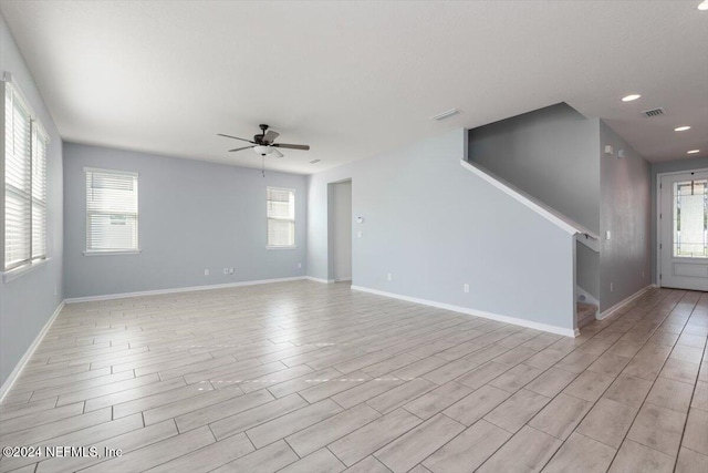 empty room featuring ceiling fan, light wood-type flooring, and a healthy amount of sunlight