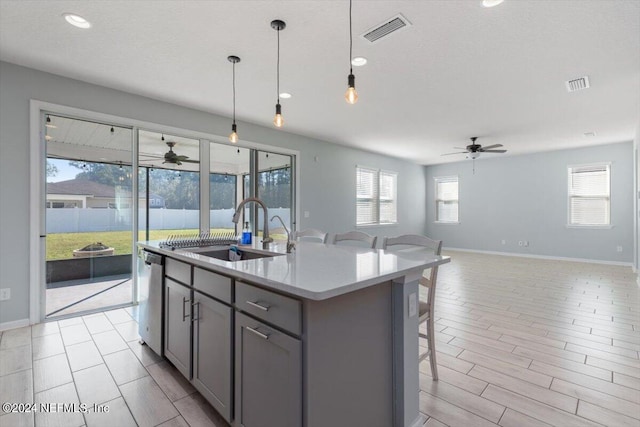 kitchen featuring a center island with sink, a healthy amount of sunlight, hanging light fixtures, and sink