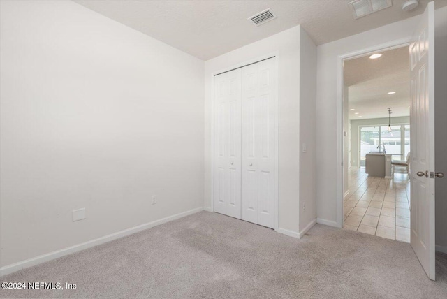 unfurnished bedroom featuring light carpet and a closet