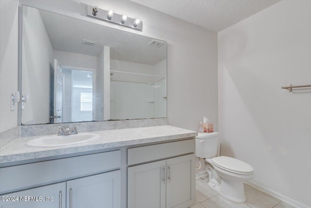 bathroom featuring walk in shower, toilet, tile patterned floors, vanity, and a textured ceiling