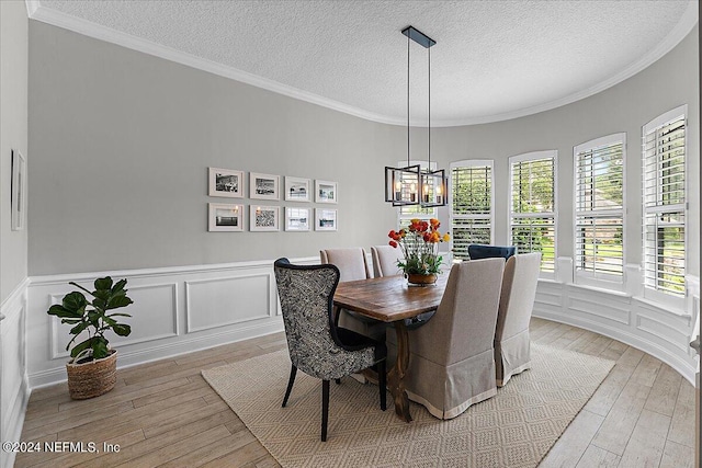 dining room with a wealth of natural light, light hardwood / wood-style flooring, a textured ceiling, and an inviting chandelier