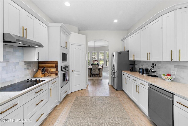 kitchen featuring light wood-type flooring, white cabinetry, stainless steel appliances, and tasteful backsplash