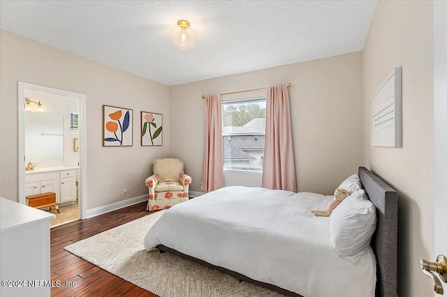 bedroom with a textured ceiling, dark wood-type flooring, and ensuite bath