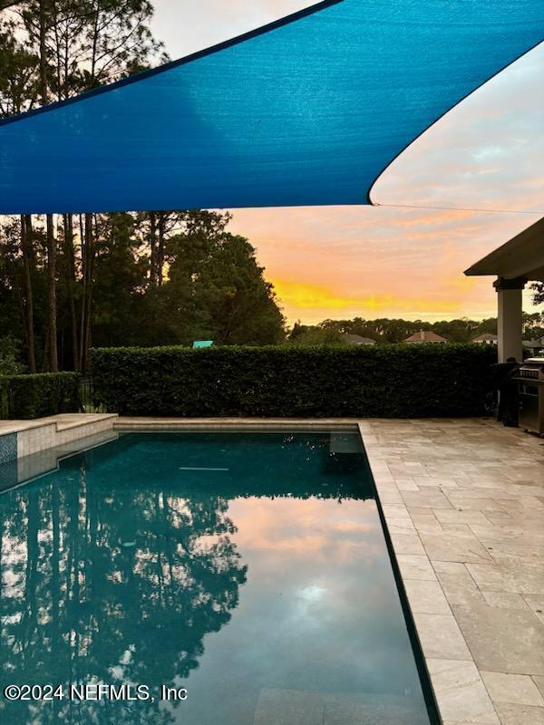 pool at dusk featuring a patio