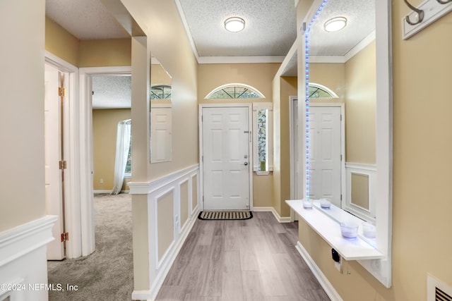 mudroom featuring ornamental molding, light hardwood / wood-style flooring, and a textured ceiling