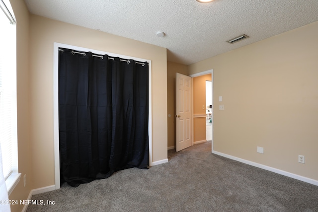 carpeted empty room with a textured ceiling