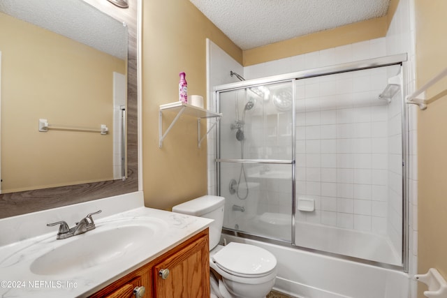 full bathroom featuring shower / bath combination with glass door, vanity, toilet, and a textured ceiling