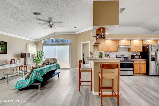 kitchen featuring light wood-type flooring, ceiling fan, stainless steel appliances, a kitchen bar, and lofted ceiling