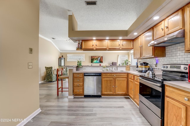 kitchen with stainless steel appliances, sink, light hardwood / wood-style flooring, and a textured ceiling