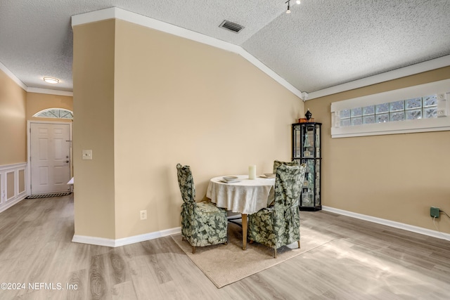 dining space with ornamental molding, lofted ceiling, hardwood / wood-style floors, and a textured ceiling