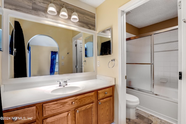 full bathroom featuring enclosed tub / shower combo, vanity, toilet, and a textured ceiling