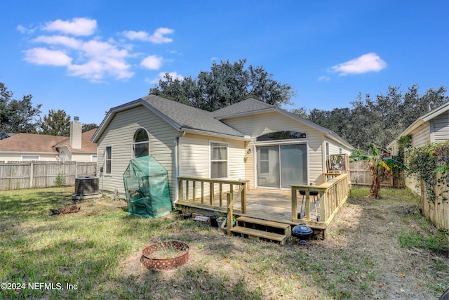 rear view of house featuring cooling unit, a lawn, and a deck