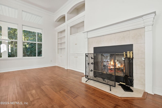 living room featuring hardwood / wood-style flooring, a fireplace, built in features, and ornamental molding