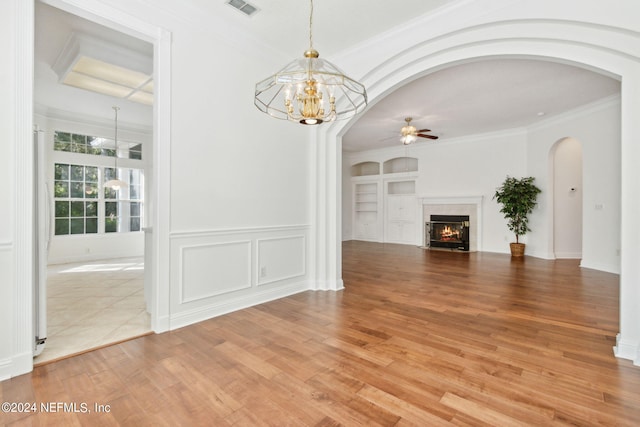 unfurnished living room featuring hardwood / wood-style flooring, ceiling fan with notable chandelier, crown molding, and a tile fireplace