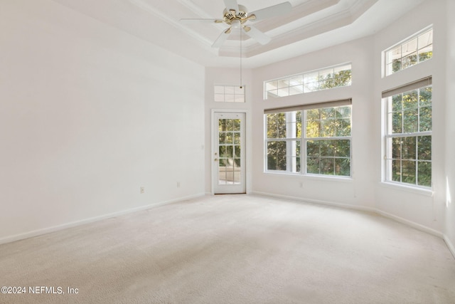 carpeted spare room with a towering ceiling, crown molding, ceiling fan, and a tray ceiling