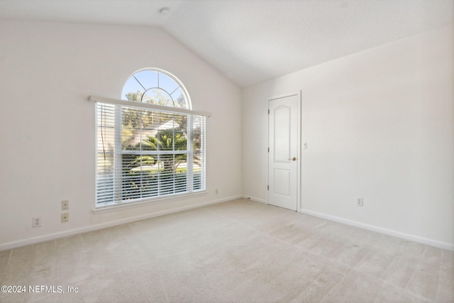 carpeted empty room featuring vaulted ceiling