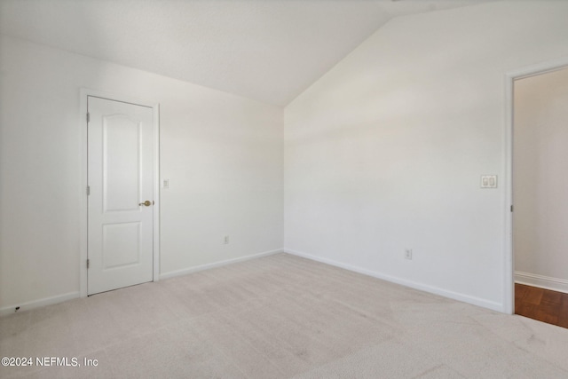 empty room featuring light carpet and vaulted ceiling