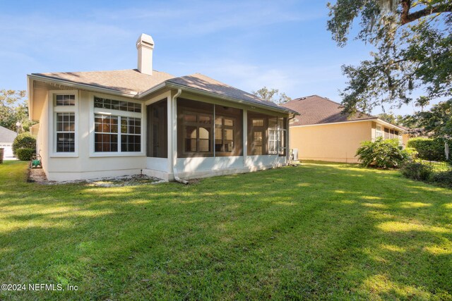 back of house with a sunroom and a lawn