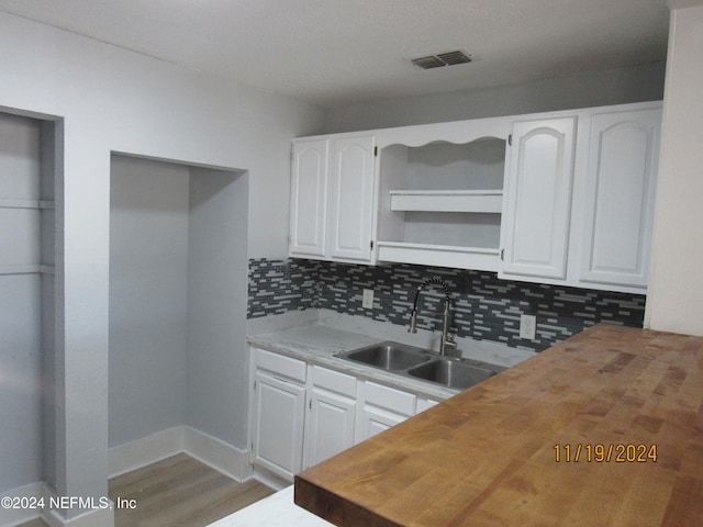 kitchen with tasteful backsplash, sink, hardwood / wood-style flooring, white cabinets, and butcher block countertops