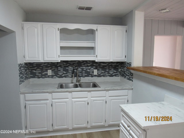 kitchen with white cabinets, decorative backsplash, and sink