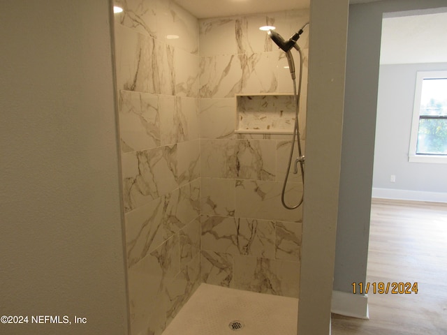 bathroom featuring wood-type flooring and a tile shower