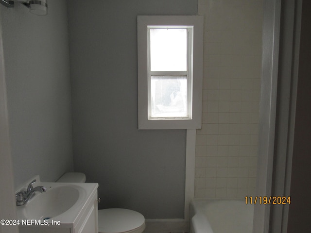 bathroom featuring vanity, toilet, and a tub