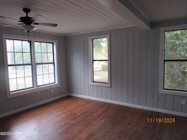 unfurnished room featuring wood walls, ceiling fan, a healthy amount of sunlight, and wood-type flooring