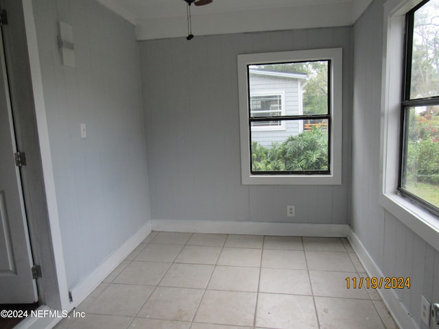 tiled spare room featuring wooden walls and plenty of natural light