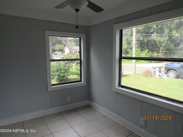 unfurnished room featuring wood walls, light tile patterned floors, and a wealth of natural light