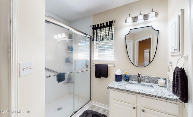 bathroom featuring vanity, a textured ceiling, a shower with door, and hardwood / wood-style floors