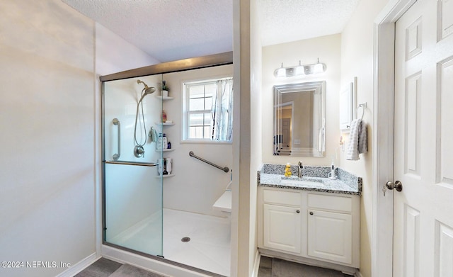 bathroom featuring a stall shower, a textured ceiling, and vanity