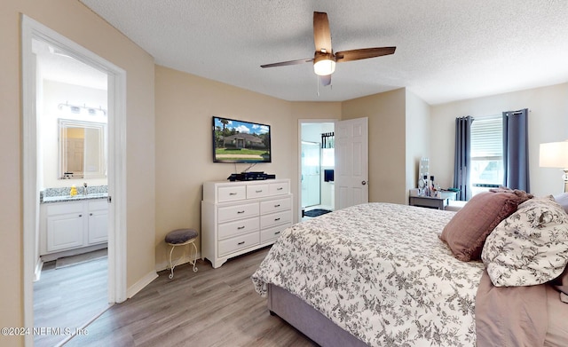 bedroom featuring light wood-style floors, a textured ceiling, connected bathroom, ceiling fan, and baseboards