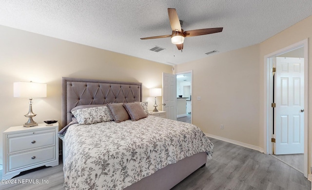 bedroom with wood finished floors, a textured ceiling, baseboards, and ceiling fan