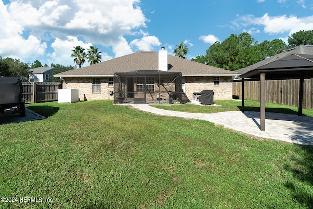 back of house with a patio area, a sunroom, a chimney, and roof with shingles
