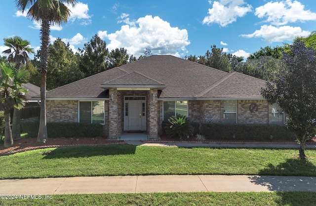 view of front of home featuring a front yard, a shingled roof, and brick siding