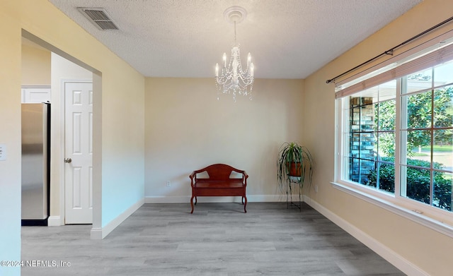 sitting room featuring a textured ceiling, a chandelier, light wood finished floors, and baseboards
