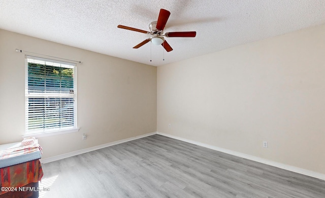 spare room featuring wood finished floors, ceiling fan, a textured ceiling, and baseboards