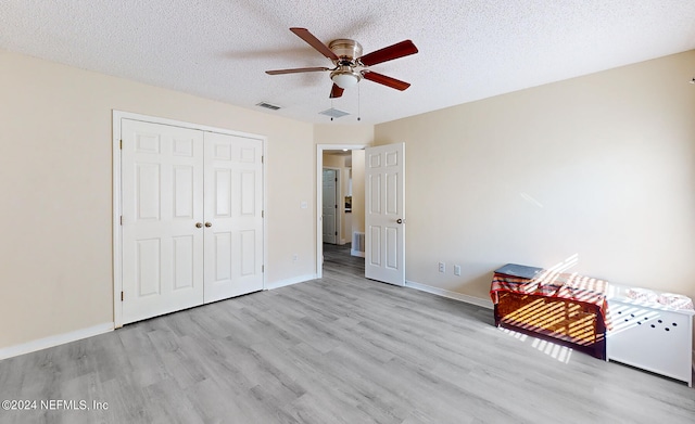 unfurnished bedroom with light hardwood / wood-style flooring, a textured ceiling, a closet, and ceiling fan