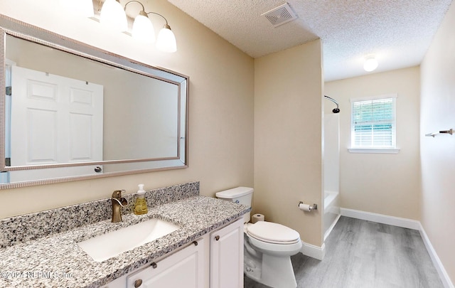 bathroom with wood finished floors, toilet, vanity, a textured ceiling, and shower / bathtub combination